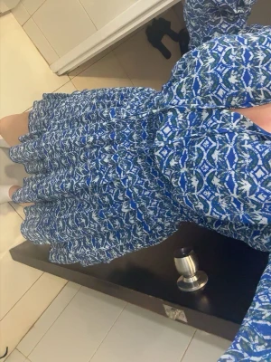 Blå mönstrad klänning  - Säljer en blå och vit kortklänning med lång ärm och elastisk midja.