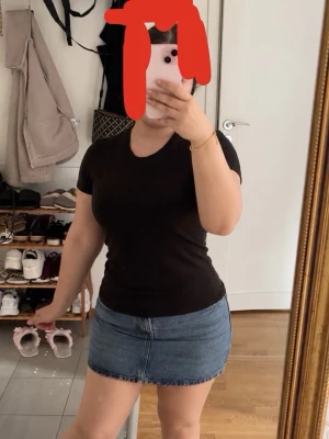 Blå jeanskjol i kort modell - Säljer en klassisk blå jeanskjol i kort modell. Kjolen har en enkel design utan synliga detaljer som knappar eller dragkedja framtill och är tillverkad i ett denimtyg. Perfekt att matcha med en t-shirt eller hoodie.