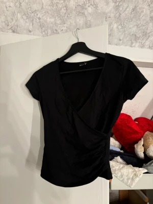 T-shirt mer V-ringning  - En svart t-shirt med djup V-ringning, scrunch vid ena sidan. Säljer då jag inte använder. Pris går att diskuteras 🤩