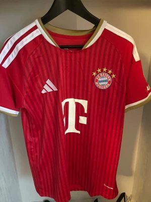 Bayern Hemma Fotbollströja Olise 26/27 - Helt ny och trendig Bayern Munchen 2026 / 2027 säsongs Hemma versionfotbollströja med Olise #17 på ryggen. Nypris runt 1099kr. Passformen på tröjan är som en oversized t-shirt i storlek S. Tröjan kommer med original förpackning och skickas i förstärkt påse för att hindra skador eller slit under frakt. Kontakta vid funderingar, och kolla min profil om du vill se andra tröjor. 