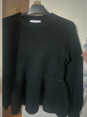 🖤 Svart stickad tröja med volang | Samsa Collection | XS - Säljer en superfin svart stickad tröja från Samsa Collection i storlek XS. Tröjan har en fin volang längst ner som ger en elegant och feminin touch. Perfekt att bära till jeans, kostymbyxor eller kjol – passar både till vardag och fest.