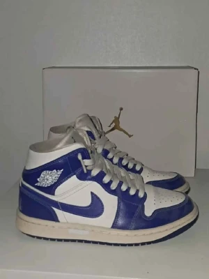 Nike Air Jordan 1 Mid blå/vit - Snygga Nike Air Jordan 1 Mid sneakers i blått och vitt läder med klassisk swoosh och Air Jordan-logga på sidan. Skorna har vita snören och en vit/blå yttersula. Perfekta för dig som gillar streetwear och vill sticka ut. Mer bilder privat!