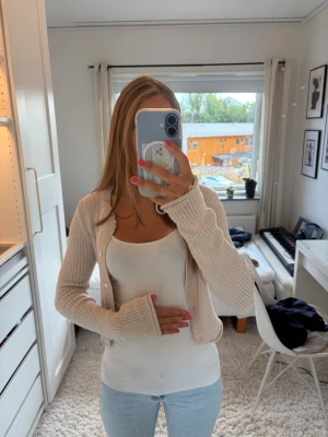 Beige ribbad kofta med knappar - Säljer en beige ribbad kofta med långa ärmar och knäppning framtill. Koftan har en croppad passform och är tillverkad i ett stickat material. Jätteskön, söt kofta perfekt över något linne 💕💕storlek står tyvärr inte kvar i koftan, men är lång i ärmarna och sitter lagom tajt på mig som vanligtvis har storlek s.