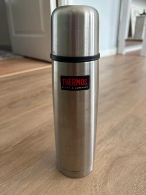 Rostfri termos från Thermos - Säljer en stilren termos i rostfritt stål från Thermos. Den är cylindrisk med en silverfärgad finish och har en svart detalj vid locket. Perfekt för att hålla drycker varma eller kalla under dagen. Den rymmer 5 dl. Kolla gärna mina andra annonser❗️