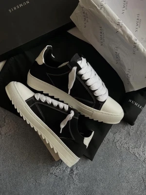 Numeris  - Stilrena sneakers i svart tyg med vita kontrastsömmar, vit tå och vit sula. Skorna har vita skosnören och en låg profil som passar till många olika outfits. Snygg detalj med vit häl och räfflad yttersula.