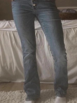 Ljusblå bootcut jeans - Säljer ett par ljusblå bootcut jeans med klassisk femficksdesign och normal midja. Jeansen har en snygg tvättad look och raka ben som går ut lite nedtill. Perfekta till sneakers eller boots för en avslappnad stil. Jag är 165cm lång🥰