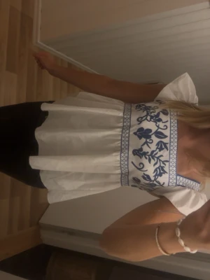 Vit blus med blå broderi och volang - Supersöt vit blus med blått broderat blommönster från shein. Storlek står inte men passar mig som har xxs-xs. Knappt använd så bra skick men nån fläck kan vara synlig💕