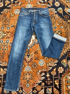 Nudie jeans - Snygga blå Nudie jeans i smal passform med klassisk femficksdesign. Jeansen har en lätt tvättad/ faded look. Materialet är denim i bomull. Bra och noggrant använda där det finns nästan inga tecken på användning, förutom Nudie jeans tagen.  Storlek är 30/32. Skriv om frågor och prisrekkomendationer!😊