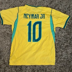 🇧🇷 Brasilien Landslagströja #10  - Säljer en ikonisk gul Brasilien-landslagströja från Nike med klassiska nummer 10 tryckt på magen! Det legendariska CBF-emblemet med de fem stjärnorna på bröstet, snygga gröna detaljer längs sidorna och kragen. 🇧🇷✨ Riktigt fräsch piece till både fotboll, träning och sommar-streetwear! 