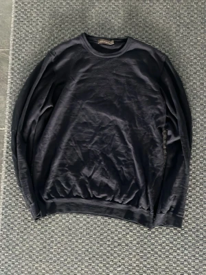 Svart basic sweatshirt från Oscar jascobsson - En enkel svart sweatshirt med rund hals och långa ärmar. Tröjan har ribbade muddar vid ärmslut och nederkant, perfekt för en clean och avslappnad stil. Passar till det mesta och är lätt att matcha med andra plagg.