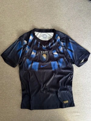 Uruguay Player Version - Säljer en snygg Uruguay fotbollströja från Nike i svart och blått med Nike’s nya Aero-FIT och klubbmärke på bröstet. Tröjan har korta ärmar och rund hals, perfekt för fotboll eller träning.