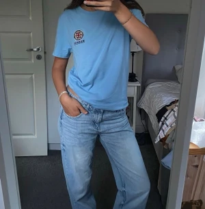 Ljusblå t-shirt från Morris - Ljusblå t-shirt från Morris med rund halsringning och tryckt logga på bröstet. Klassisk passform och tillverkad i mjuk bomull, perfekt till jeans eller shorts.