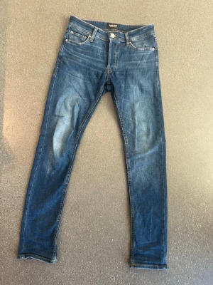 Blå Jack an Jones jeans - Snygga blå jeans från Jack and Jones med lätt slitning och klassisk femficksdesign. Jeansen är i väldigt fint skick! Inga tecken på användning. Modellen heter Slim Glenn och är i storlek W28 L32.