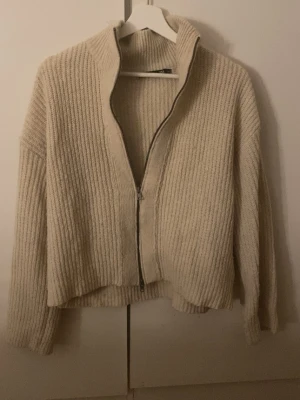 Beige ribbstickad ziptröja - Säljer denna as sköna zip tröjan som är perfekt till att slänga över sig närmare kvällen!