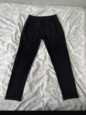 Svarta mjukisbyxor med resårmidja - Svarta mjukisbyxor med rak passform och resår i midjan. Byxorna är enkla och stilrena, perfekta för en avslappnad look. Tillverkade i mjukt material som känns skönt mot huden.
