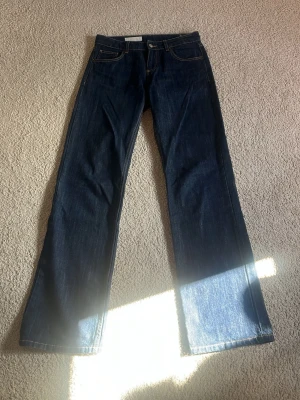 Mörkblå straight low waist jeans från ZARA - Säljer ett par mörkblå raka jeans i low waist från ZARA med klassisk femficksmodell och kontrastsömmar. Jeansen har hög midja och är tillverkade i ett kraftigt denimtyg. Perfekta för dig som gillar en tidlös och avslappnad look.