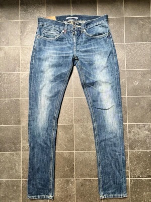 Blå slitna jeans med raka ben - Säljer ett par blå jeans med snyggt sliten tvätt och raka ben. Jeansen har klassisk femficksmodell, ljusa partier framtill och kontrastsömmar. Perfekta för en avslappnad och trendig look.