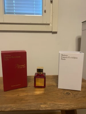 Maison Francis Kurkdjian Baccarat Rouge 540 - Lyxig parfym i en elegant röd glasflaska med guldfärgad etikett och lock. Doften är Baccarat Rouge 540 Extrait de Parfum, känd för sin unika och exklusiva karaktär. Kommer med både röd och vit förpackning som ger en exklusiv känsla.