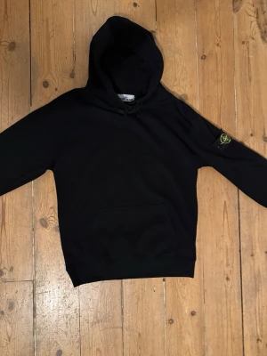 Svart hoodie från Stone Island - Säljer en svart hoodie från Stone Island med klassisk patch på vänster ärm. Hoodien är använde vid något tillfälle men annars helt ny.