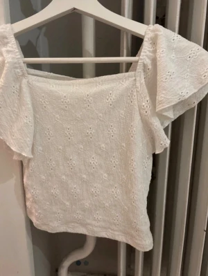 Vit blus med broderade detaljer - Söt vit blus med broderade detaljer och korta, vida ärmar. Har använt den 2-3 gånger. Den kommer från kappahl i storlek 146/152🩷