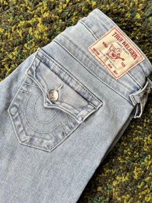 Ljusblå true religon jeans  - Säljer ett par ljusblå boutcut jeans från true religon. De i storlek 23, köpt för 1200 från början. Jeansen är lite slitna längst ner (kolla sista bilden)💗