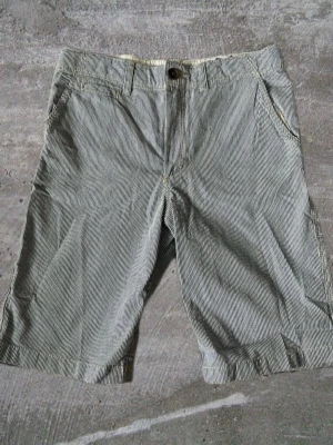 Randiga shorts i bomull - Snygga randiga shorts i bomull med klassisk passform. De har fickor fram och bak, bälteshällor och stängs med knapp och dragkedja. Perfekta för varma dagar och en avslappnad stil.