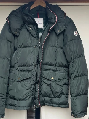 Mörkgrön dunjacka från Moncler - Moncler dunjacka, i godtagbart skick. Jackan är äkta och koden kan skickas för att bevisa det. Moncler size 3 men passar som en medium eller small. En perfekt och billig snygg dunjacka från Moncler! Nypris 16000 svenska kronor. Lagning gjord på vänster del av rygg och små skador förekommer, kolla på bilderna för att bedöma skick.