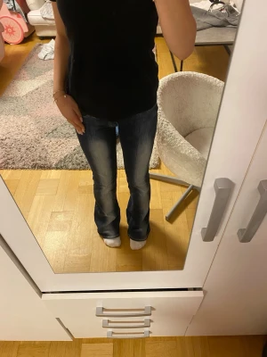 Mörkblå bootcut Cheap Monday jeans - Säljer ett par mörkblå bootcut jeans med snygga slitningar och lätt utsvängda ben. Jeansen har klassisk femficksdesign och normal midja. Perfekta till sneakers eller boots för en avslappnad look. Dem är ett fåtal gånger använda. Taggen där bak har gått sönder men sitter på plats, annars finns det inga märken på användning. 