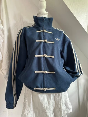 Adidas rare tang jacket - CNY vintage jacket I dusty blue, äldre modell. Köpte second hand, använt fåtal gånger själv. Säljer då jag vill köpa en annan färg! Storlek M, perfekt oversize på mig (1.69cm)
