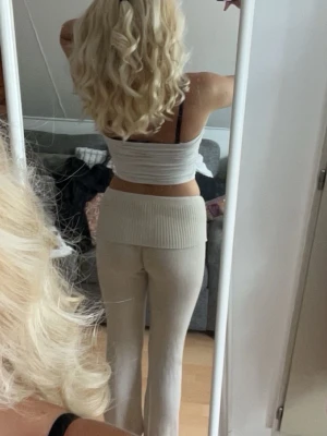 Beige ribbade byxor  - Säljer ett par beige byxor med bred ribbad linning och lätt utsvängda ben. Materialet är mjukt och stretchigt.