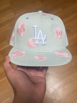 New Era 59FIFTY Dodgers Floral Cap - New Era 59FIFTY fitted cap i den populära Hand Stitched Floral-designen för Los Angeles Dodgers. Kepsen är i mycket bra skick och redo att bäras.