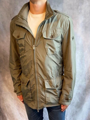 J-Lindberg Fieldjacket olivgrön - Stl M - Riktigt snygg Höst/vår fieldjacket från J-Lindeberg i färgen olivgrön 🫒! | Mycket bra skick: 9/10, Inga defekter | Stl: M, modellen är 178cm och väger 78kg, passar bra mellan 182-197cm beroende på hur man vill att den ska sitta (lång modell)  🙌  | Hör av dig vid frågor // Galgen 🫡 Har fler Jackor i profilen samt om du köper mer plagg blir de billigare!