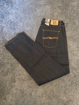 Mörkblå jeans från Nudie Jeans - Säljer ett par mörkblå jeans från Nudie Jeans i rå denim och är selvedge. De är helt o tvättade med prislappen kvar. Modellen är steady Eddie. Hör av er vid funderingar. 