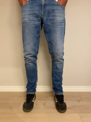 Blå slim fit jeans med fem fickor - Snygga blå slim fit jeans med klassisk femficksdesign och lätt slitna detaljer. Jeansen har normal midja och raka ben, tillverkade i ett stretchigt denimtyg för extra komfort. Perfekta för en avslappnad och trendig look.
