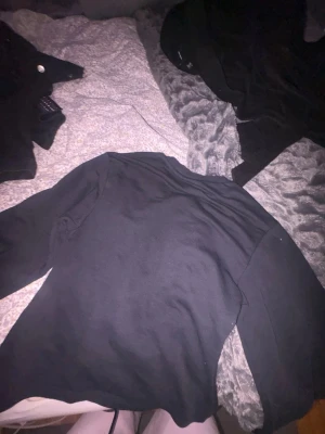 Svart långärmad tröja 157 - En basic svart långärmad tröja från 157. Tröjan har rund halsringning och är gjord i ett mjukt, stretchigt material som passar perfekt till alla outfits. Enkel och stilren design som är lätt att matcha.