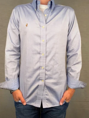 Ralph lauren skjorta ljusblå M - Säljer denna otroligt snygga ralph lauren skjorta. Riktigt skönt material . Size 15 1/2 som motsvarar M. Modellen är 180cm. Bredd 46cm,  längd 68cm! Fint skick, nytvättad och ny strykt så att skillnaden på denna och en ny ska vara minimal! Fraktar samma dag som köp, kan gå ner i pris vid snabb affär! 🤩