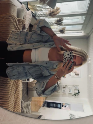 Oversized ljusblå jeansjacka - Säljer en oversized ljusblå jeansjacka med klassisk krage och stora fickor framtill. Jackan har en avslappnad passform och knäpps med silverfärgade knappar. Perfekt att slänga över en crop top för en chill look.