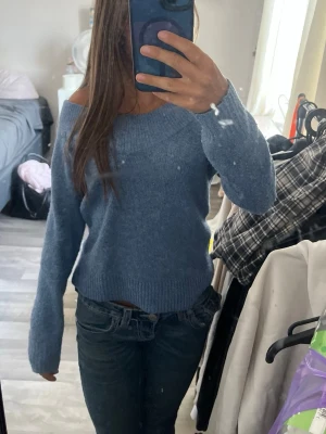 Blå offshoulder stickad tröja H&M XS - Mysig blå stickad tröja från H&M i storlek XS. Tröjan har en bred ribbad kant och offshoulder-modell som ger en snygg och avslappnad vibe. Perfekt för kyliga dagar när du vill vara både bekväm och stilren.
