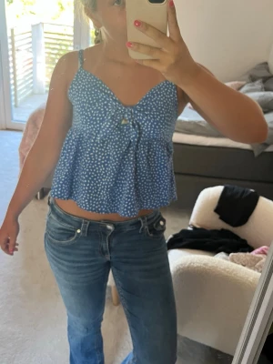 Blå prickig blus med smala axelband - Söt blå blus med vita prickar och smala axelband. Blusen har en lätt utsvängd passform och en liten knutdetalj framtill. Perfekt för sommardagar och enkel att matcha med jeans eller kjol. Från SHEIN och har blivit för liten men älskar den!!