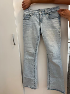 Ljusblå bootcut jeans - Snygga ljusblå bootcut jeans med klassisk femficksdesign och låg midja. Jeansen har en lätt tvättad look och vida ben nedtill. Perfekta för en avslappnad och trendig stil. Materialet är denim i bomull.