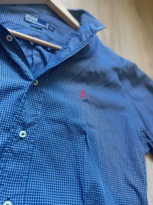 Ralph Lauren Skjorta 👔  - Ralph Lauren skjorta – Strl L 🔥 Blårutig skjorta från Ralph Lauren med klassisk passform och broderad logotyp på bröstet. Stilren modell som passar lika bra till vardag som mer uppklädda tillfällen. I fint begagnat skick.  📏 Storlek: L 📦 Skick: Bra begagnat skick 💬 Hör gärna av dig vid frågor eller om du vill ha fler bilder!