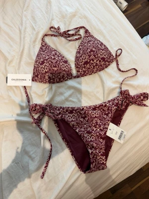 Vinröd bikini med blommönster Calzedonia - Snygg vinröd bikini från Calzedonia med vitt blommönster. Överdelen har trekantsform och knyts i nacken och ryggen, medan underdelen har knyt i sidorna. Perfekt för sommaren och strandhäng! Nypris 918, mitt 729. Pris kan diskuteras och delarna kan av omständigheter säljas separat