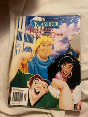 Ringaren i Notre Dame Klassiker - En färgglad klassikerbok med tecknade karaktärer från Ringaren i Notre Dame. Omslaget har blå, gul och rosa färginslag och boken är i pocketformat. Perfekt för dig som gillar äventyr och Disney-inspirerade berättelser.