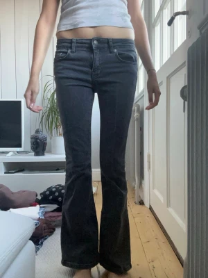Svarta bootcut jeans med låg midja - Snygga svarta bootcut jeans med låg midja och klassiska fem fickor. Jeansen har en lätt utsvängd passform nertill och synliga sömmar. Perfekta för en trendig och avslappnad look.