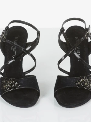 Svarta pumps från Louis Vuitton - Snygga svarta pumps från Louis Vuitton med smala korsade remmar och öppen tå. Dekorerade med nitar framtill och har en elegant hög klack. Tillverkade i glansigt material med klassisk logga på innersulan. Perfekta för dig som vill ha en lyxig och trendig look.