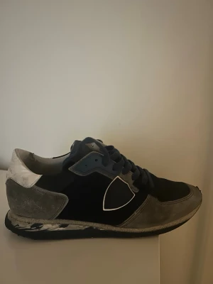 Philippe Model sneakers - Säljer mina snygga sneakers i blått och grått med mockadetaljer och vita inslag. Sulan är camouflage färgad på sidan. Nypris:2600