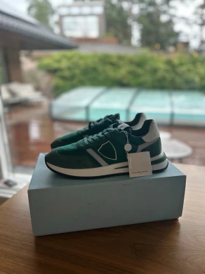 Oanvända Philippe Model 44 Herrskor Grön - Snygga sneakers från Philippe Model i grön mocka, perfekta under sommaren. Skorna har aldrig haft en fot i sig, aldrig klivit ett steg, sprillans nya som ni kan se på den andra bilden. De är självklart äkta och kvitto ingår. Antingen kan ni hämta dem i sollentuna eller så kan jag frakta de med köparskydd. Storleken är 44. nypris ligger på 3200kr, mitt pris endast 1799kr.