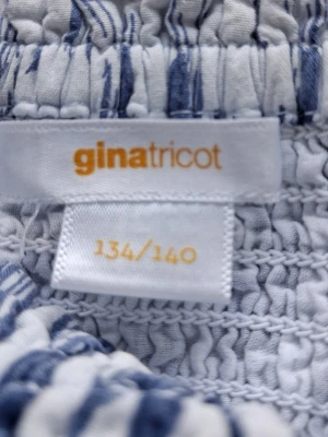 Blåvit smockad tubtopp Gina Tricot - Blåvit smockad tubtopp från Gina Tricot med abstrakt mönster. Toppen är ärmlös och har stretchig passform, perfekt för sommaren. Tillverkad i mjuk bomull som känns skön mot huden. I storlek 134/140