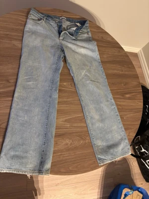 Ljusblå raka jeans - Säljer ett par ljusblå jeans med rak passform och klassisk femficksdesign. Jeansen har normal midja och dragkedja med knapp. Materialet är denim i bomull och benen har en något sliten look för en avslappnad stil.