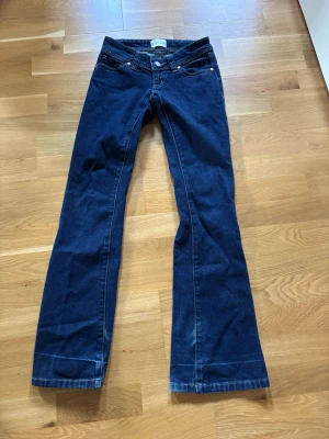 Mörkblå bootcut jeans - Snygga mörkblå bootcut jeans i klassisk modell med fem fickor och kontrastsömmar. Jeansen har låg midja och utsvängda ben. Märket heter Abrand jeans skick 7/10 de är slitna nertill.
